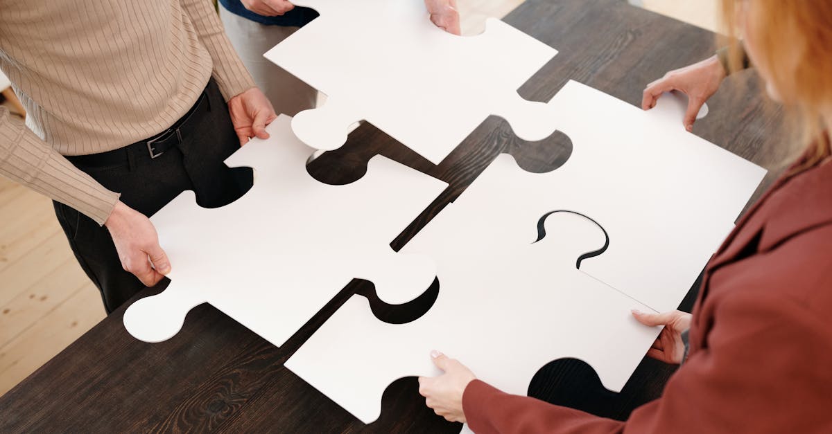 Four people collaborate by assembling large white puzzle pieces on a table.